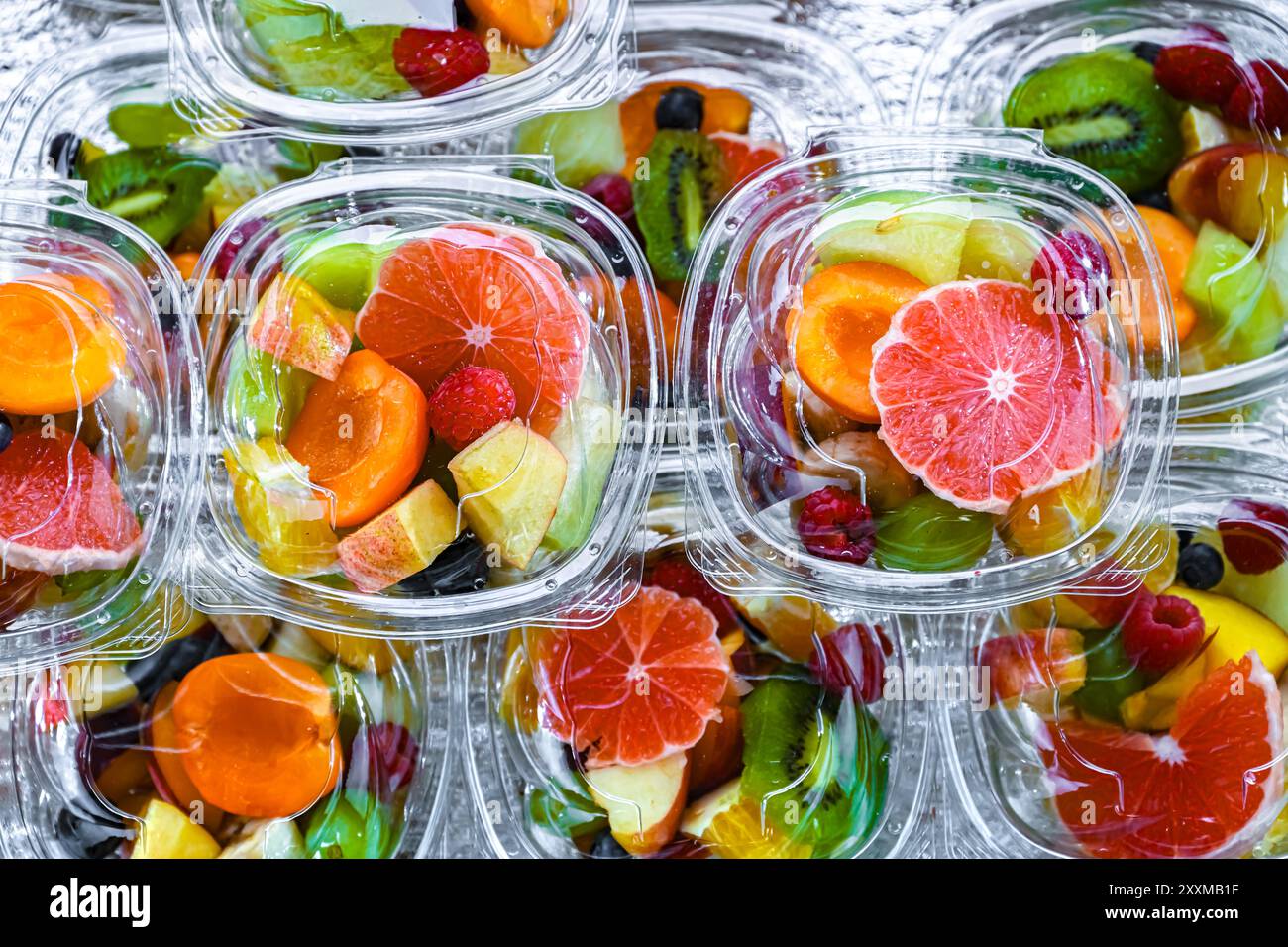 Scatole di plastica con macedonie di frutta preconfezionate, messe in vendita in un frigorifero commerciale Foto Stock