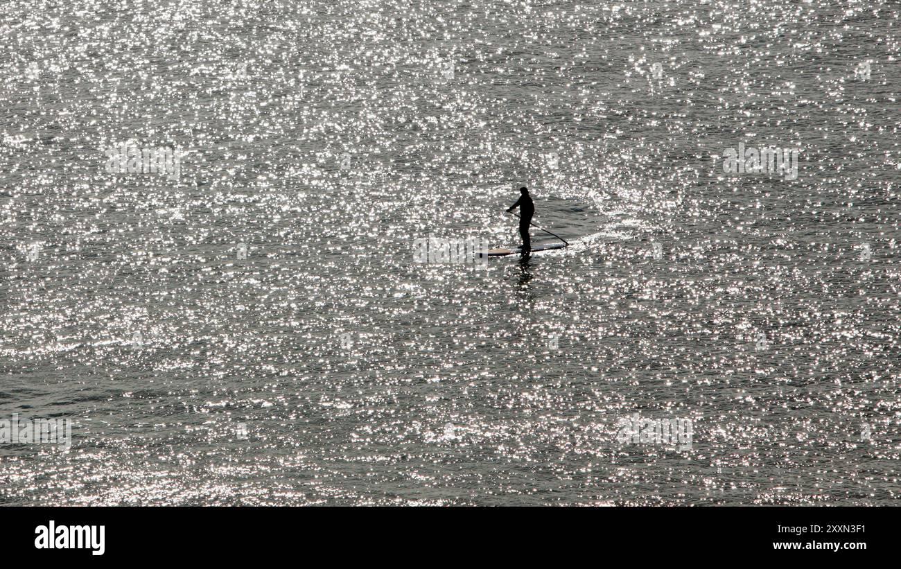 oceano con la silhouette di una persona che fa il paddle boarding a distanza dall'alto Foto Stock