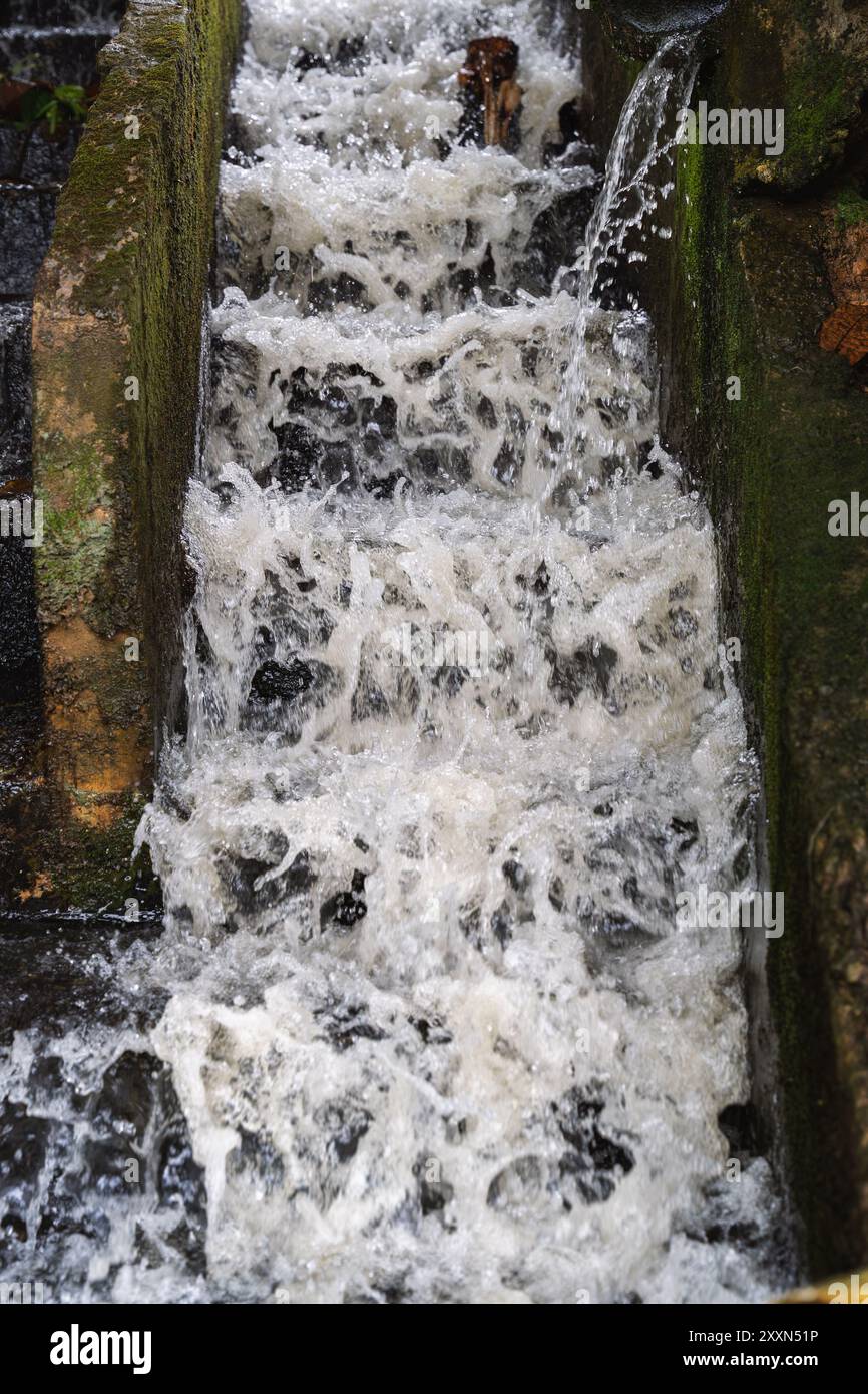 L'acqua scorre attraverso un vecchio canale di drenaggio del calcestruzzo. Foto Stock