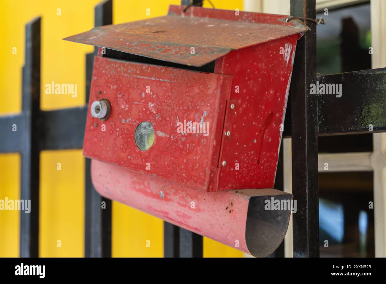 Cassetta postale rossa vintage su recinzione nera con fascino rustico. Foto Stock