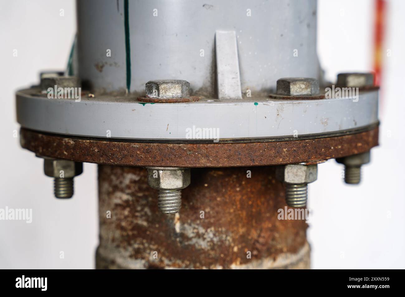 Foto ravvicinata del raccordo del tubo flangiato arrugginito con bulloni in un ambiente industriale. Foto Stock