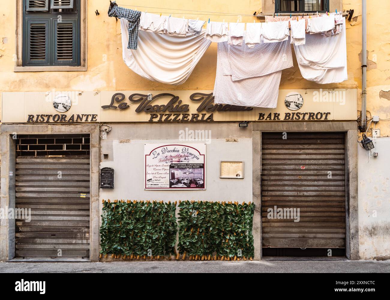 Scorcio pittoresco del quartiere Venezia nuova, con ristorante tipico e lavanderia appesa alla clothesline per tingere, Livorno, Italia Foto Stock