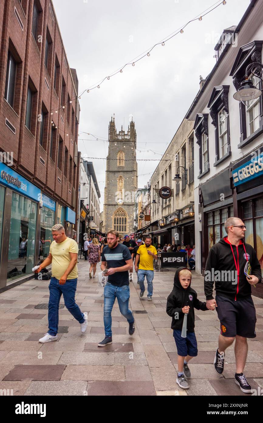 Gli amanti dello shopping e della gente in Church Street, nella capitale gallese di Cardiff, con vista sulla chiesa parrocchiale di St John the Baptist City, Galles Foto Stock