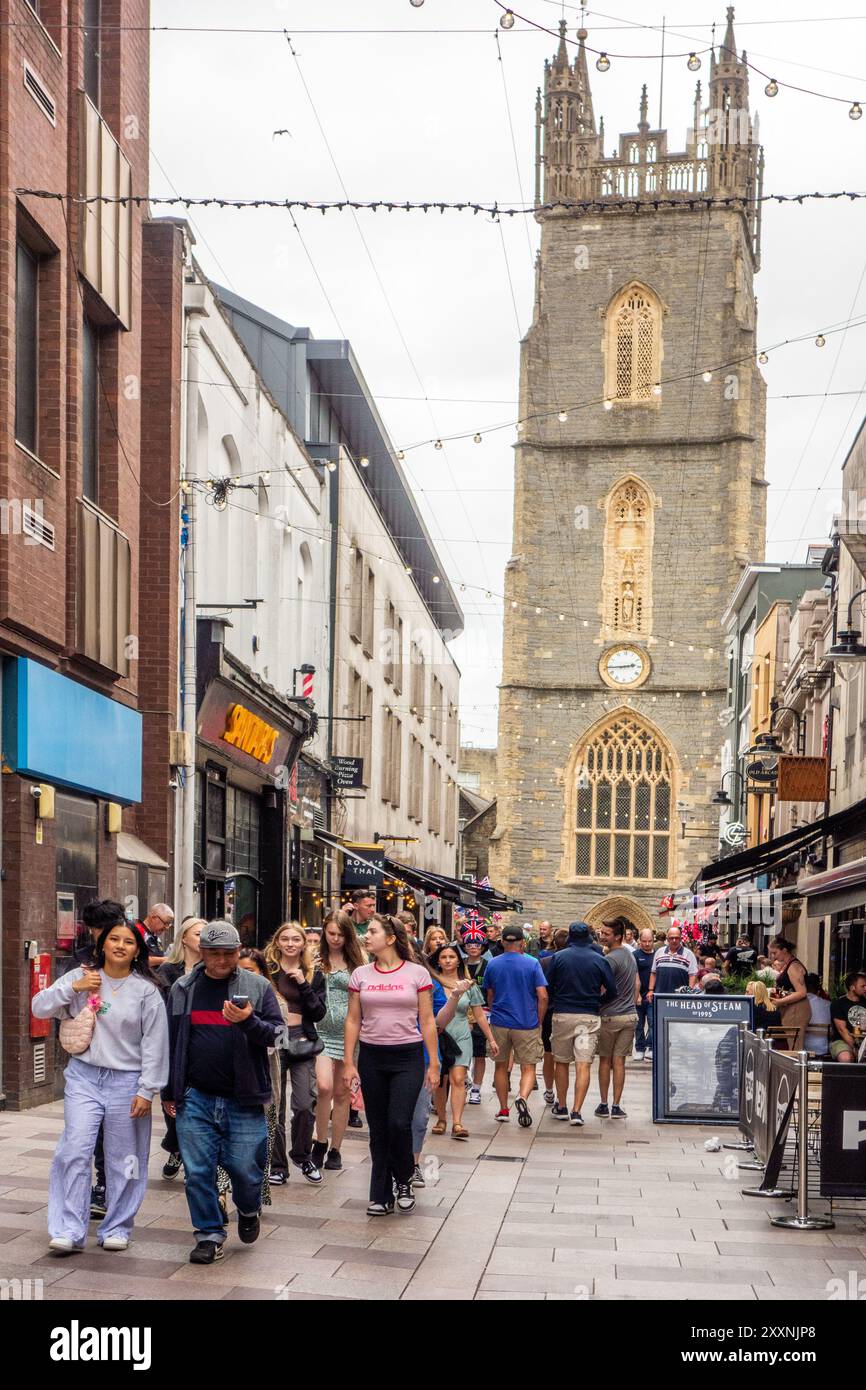 Gli amanti dello shopping e della gente in Church Street, nella capitale gallese di Cardiff, con vista sulla chiesa parrocchiale di St John the Baptist City, Galles Foto Stock