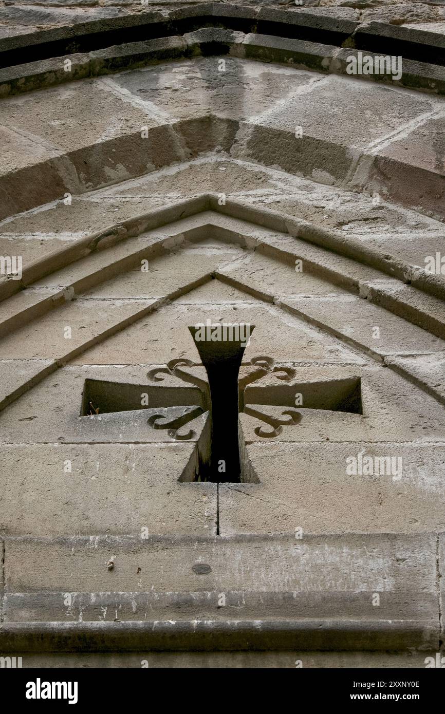 Una vera porta spagnola con una croce. Croce cattolica in stile gotico su un edificio storico Foto Stock