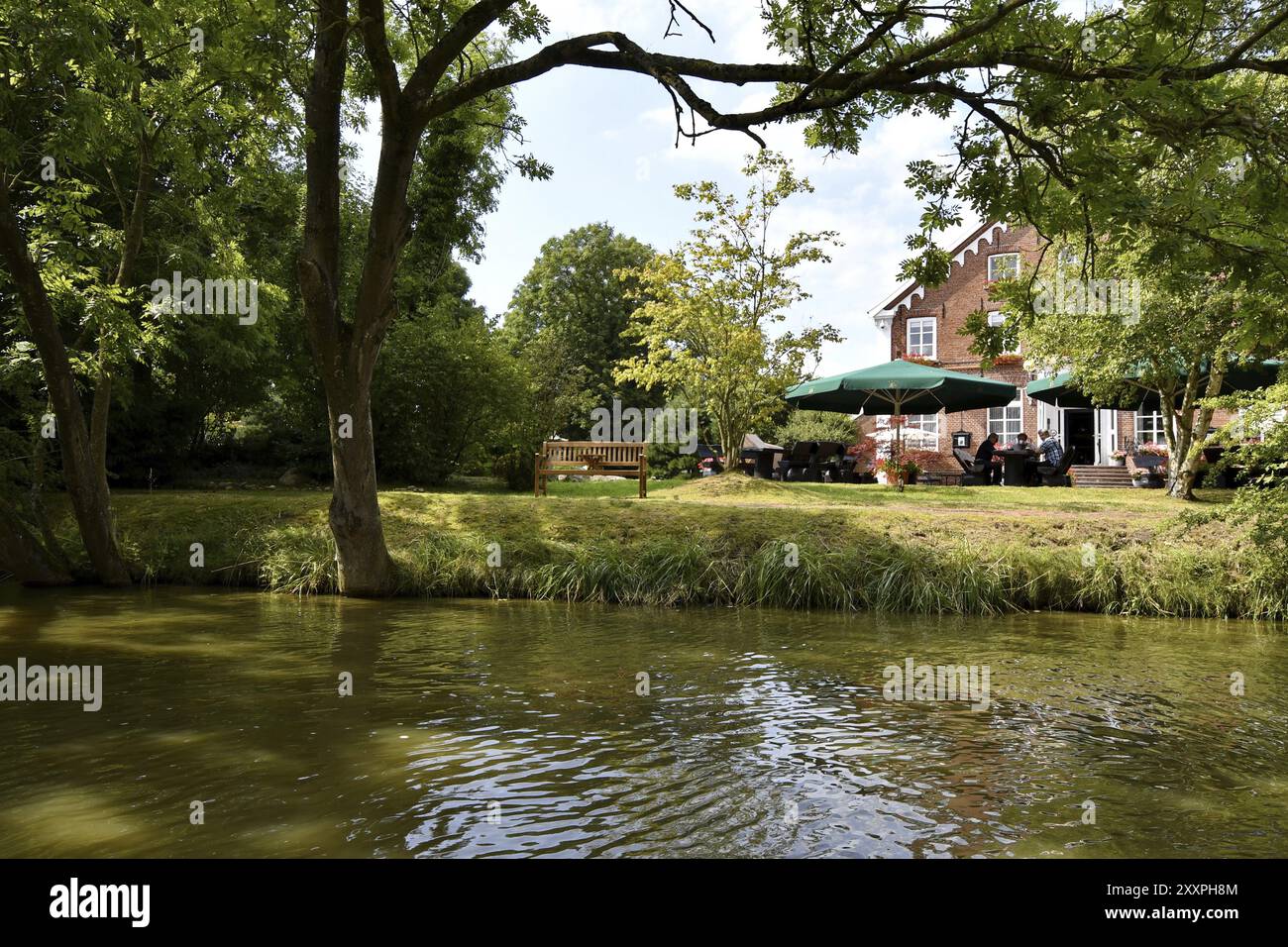 Accogliente caffetteria sulla riva del fiume circondata da alberi e natura con posti a sedere all'aperto, Greetsiel Foto Stock
