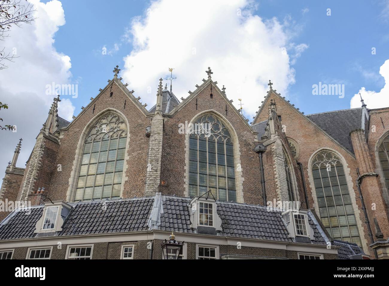 Finestre gotiche della chiesa e architettura in mattoni sotto un cielo leggermente nuvoloso, Amsterdam, Paesi Bassi Foto Stock