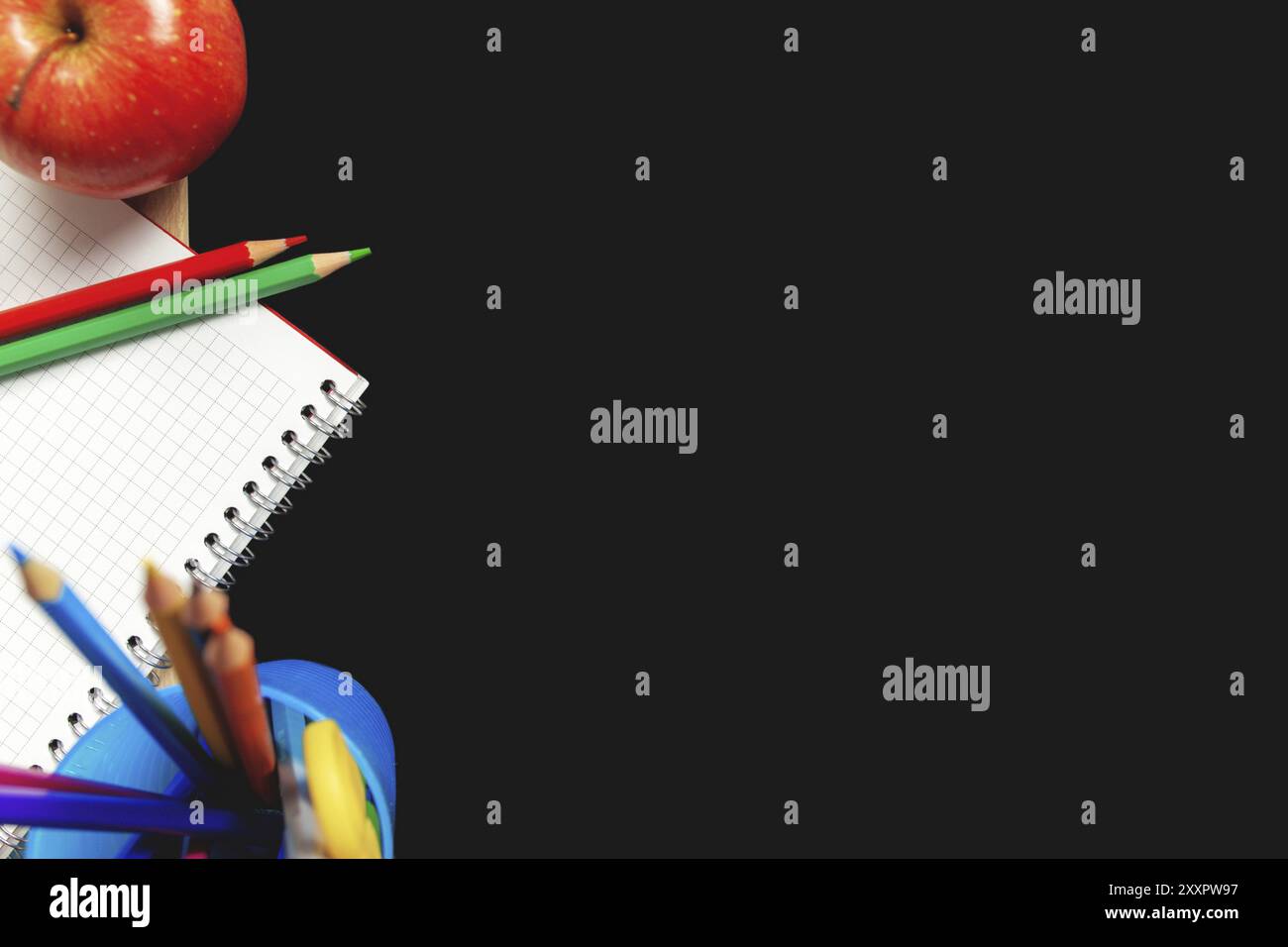 Piatto con concetto di scuola su sfondo nero con spazio vuoto fronte con vari accessori scolastica, penne, matita, blocco note, mela, forbici Foto Stock