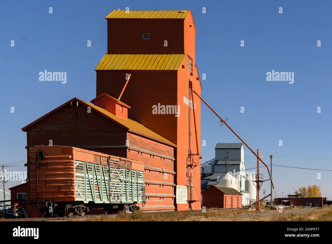 Un elevatore per cereali si trova a Nanton, nel sud dell'Alberta, vicino a un vecchio vagone ferroviario e a un edificio per la pulizia dei semi. Foto Stock
