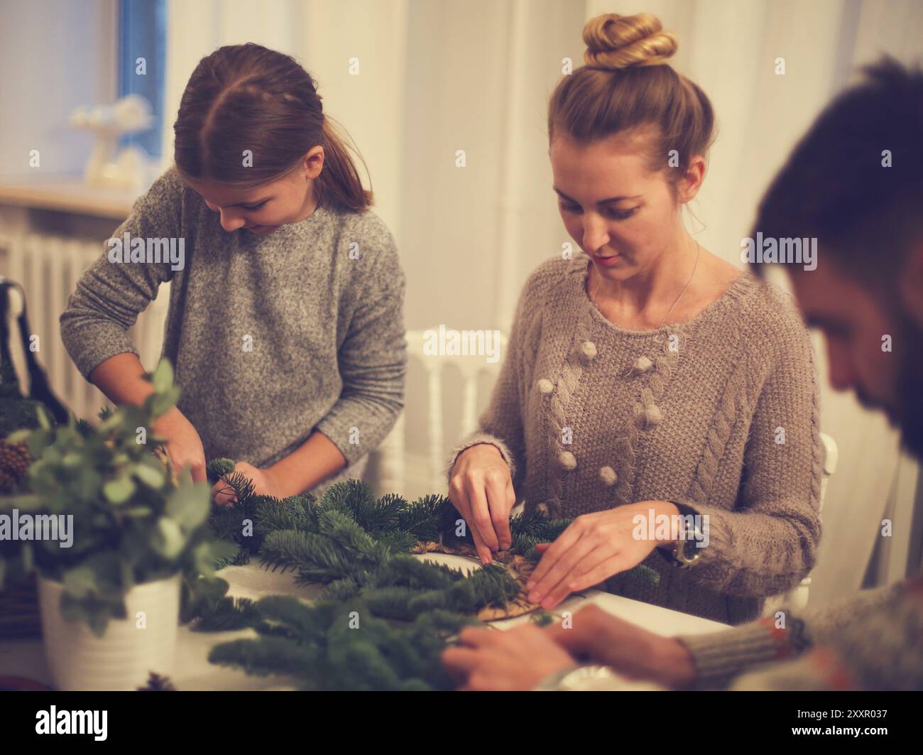 La famiglia felice facendo una corona di Avvento con la figlia insieme Foto Stock