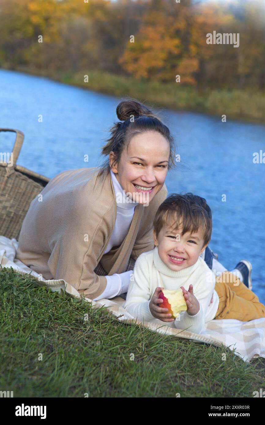 Piuttosto giovane madre con il suo piccolo figlio in autunno parco vicino al lago Foto Stock