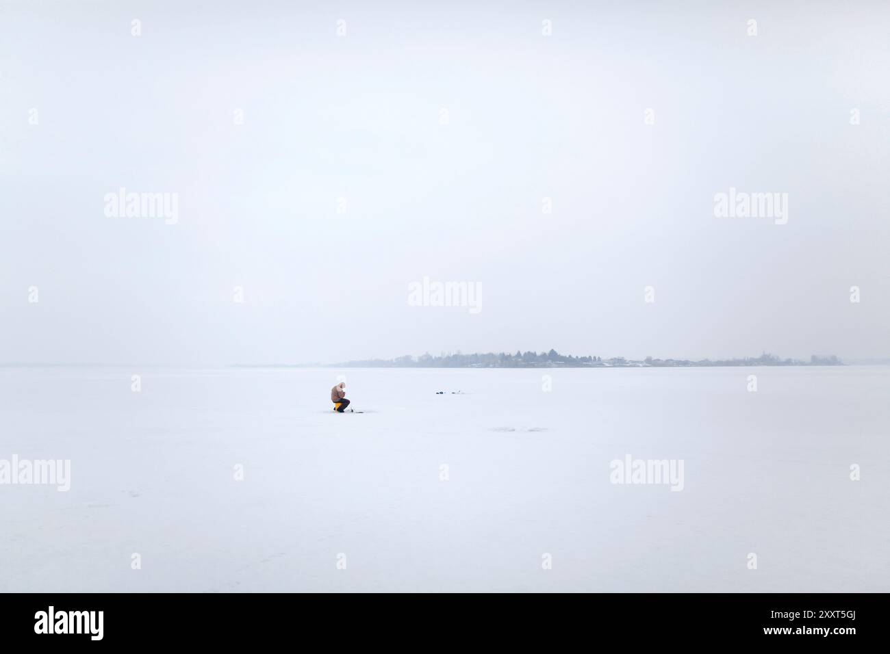 Un pescatore di ghiaccio canadese francese si trova sul lago Frozen Moses a Moses Lake, Washington Foto Stock