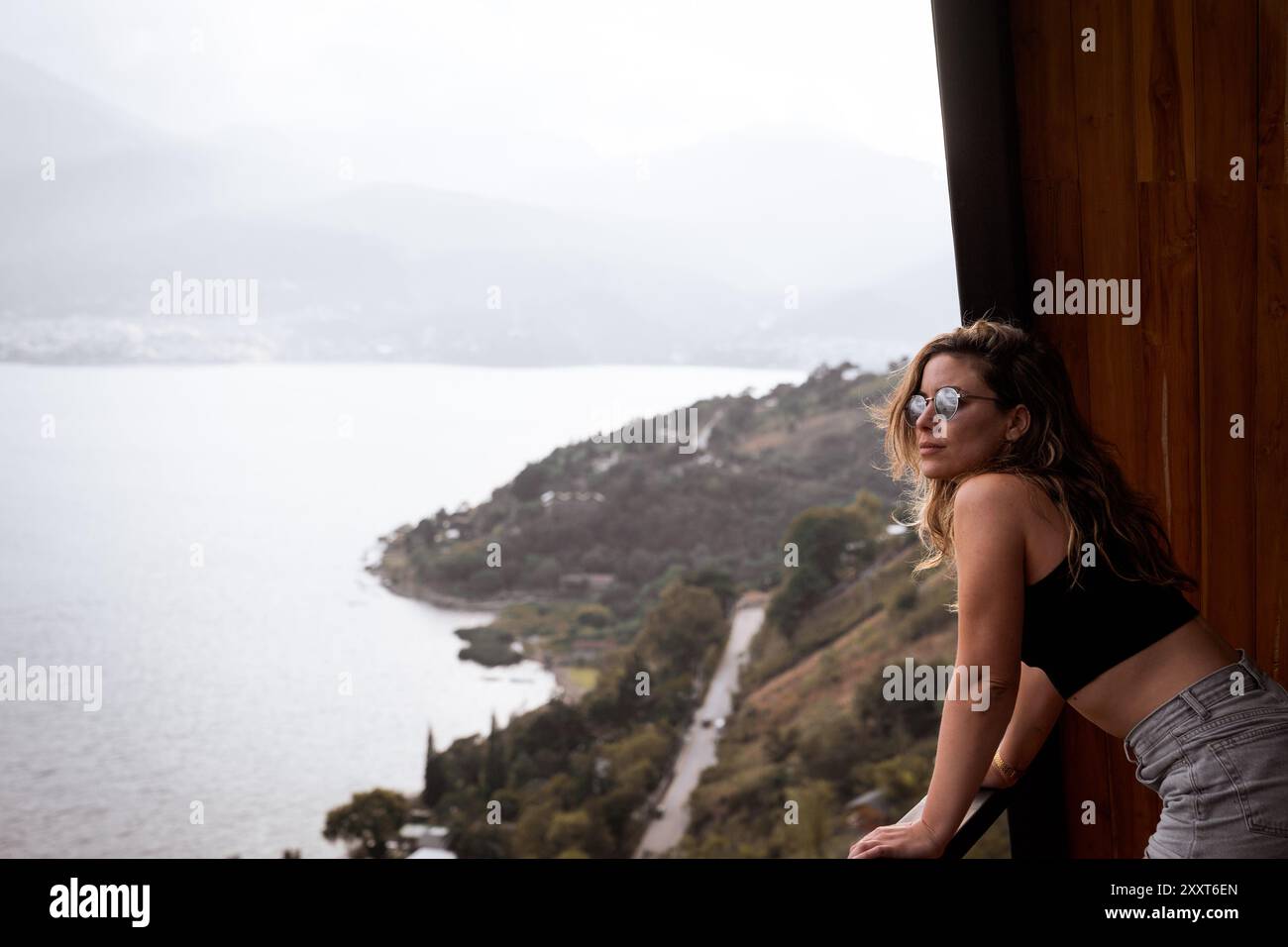 Giovane donna che gode della vista sulle montagne e sul lago dalla cabina in Guatemala Foto Stock