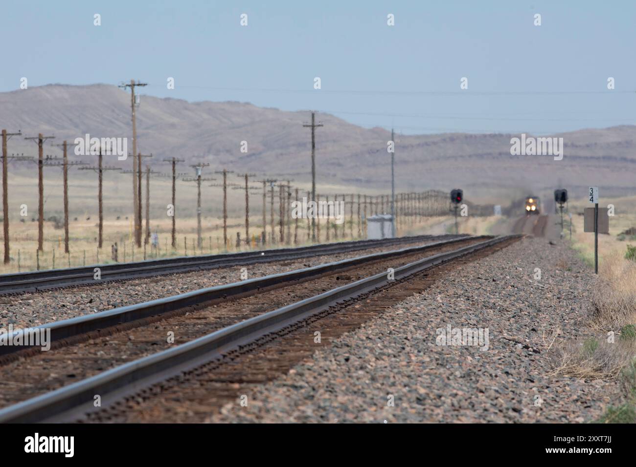 Binari che guardano lungo la linea verso un faro in lontananza Foto Stock