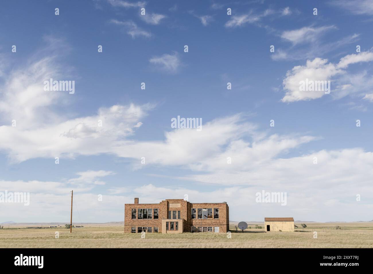 Un edificio scolastico abbandonato in un campo panoramico Foto Stock