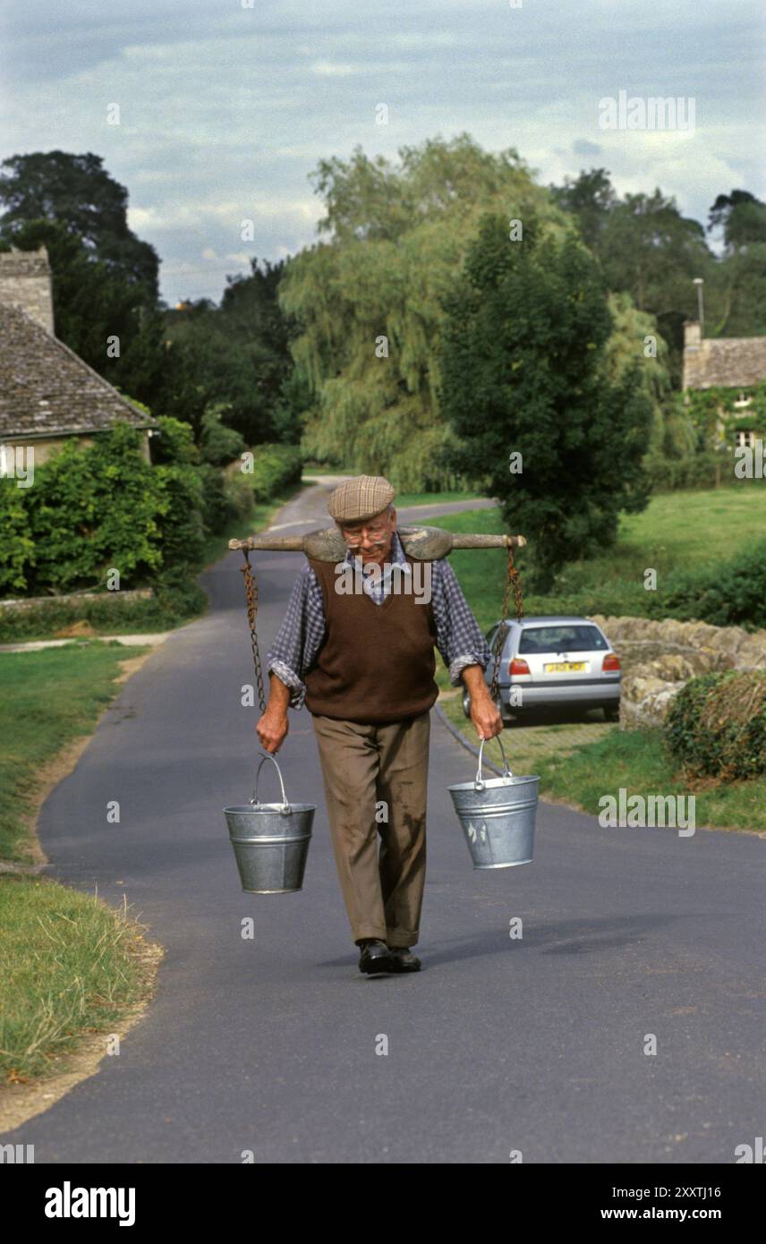 Raccolta di acqua potabile del fiume 1990s Regno Unito. John Blackwell per oltre 50 anni ha raccolto acqua ogni giorno alle 16:00 dal fiume Leach. Non si fida dell'acqua di rubinetto in casa sua e preferisce fare quello che lui e la sua famiglia hanno sempre fatto. Crede che l'acqua del rubinetto sia contaminata. English Village Life, Eastleach Turville, Gloucestershire, Inghilterra agosto 1993 HOMER SYKES Foto Stock