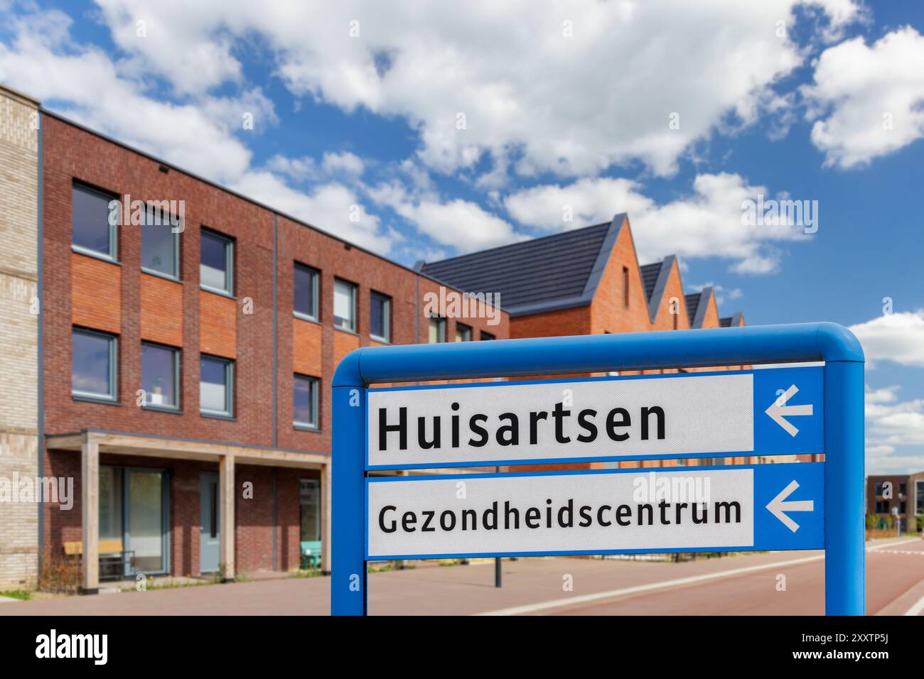 Cartello stradale con il testo olandese per "medici di famiglia e centro sanitario" in una zona residenziale con nuove case Foto Stock
