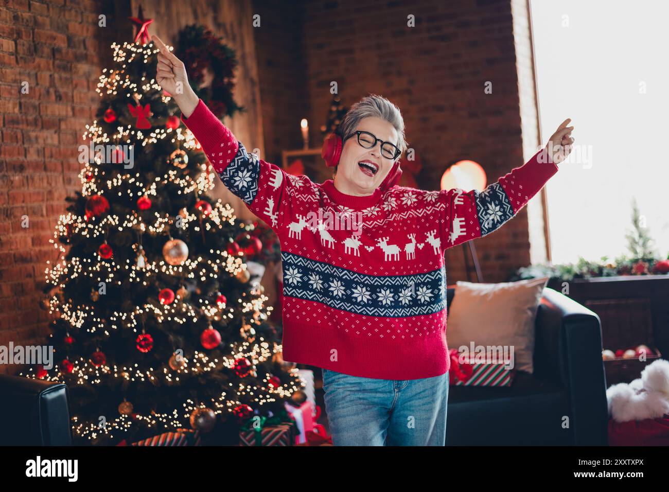 Ritratto di una persona positiva divertiti a ballare punta dita ascoltare canzoni di natale cuffie decorate casa in interni Foto Stock