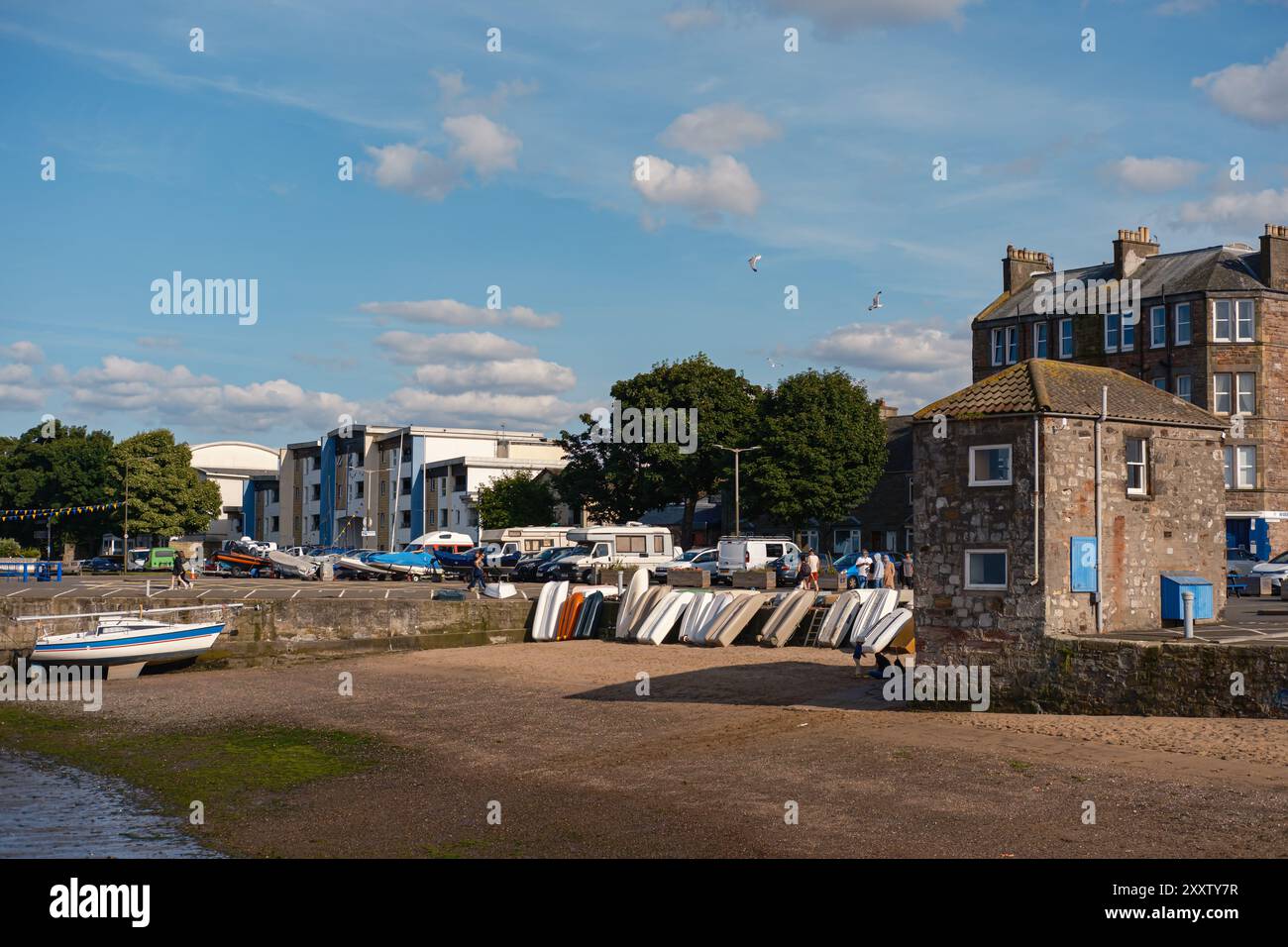 EDIMBURGO - 28 LUGLIO 2024: Un affascinante edificio per uffici di Fisherrow Harbour si trova sulla riva, con barche e deposito kayak lungo la spiaggia. Foto Stock