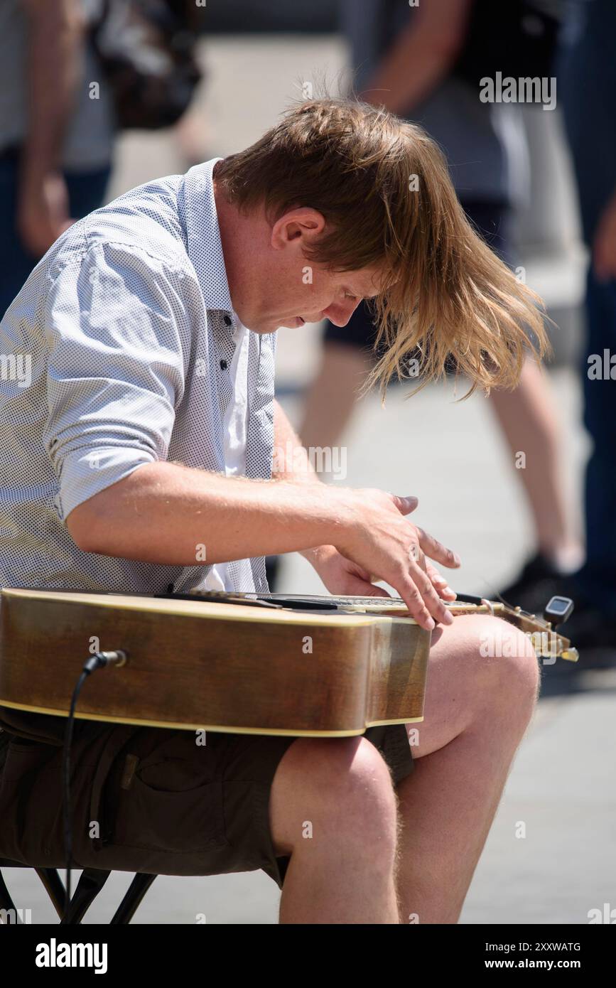 Londra, Regno Unito. Busker a Trafalgar Square che suona la chitarra con tecnica di percussione in stile lap Foto Stock