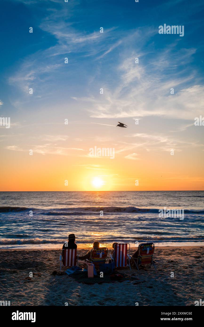La famiglia а sta guardando il tramonto su una spiaggia di Venice, Florida Foto Stock