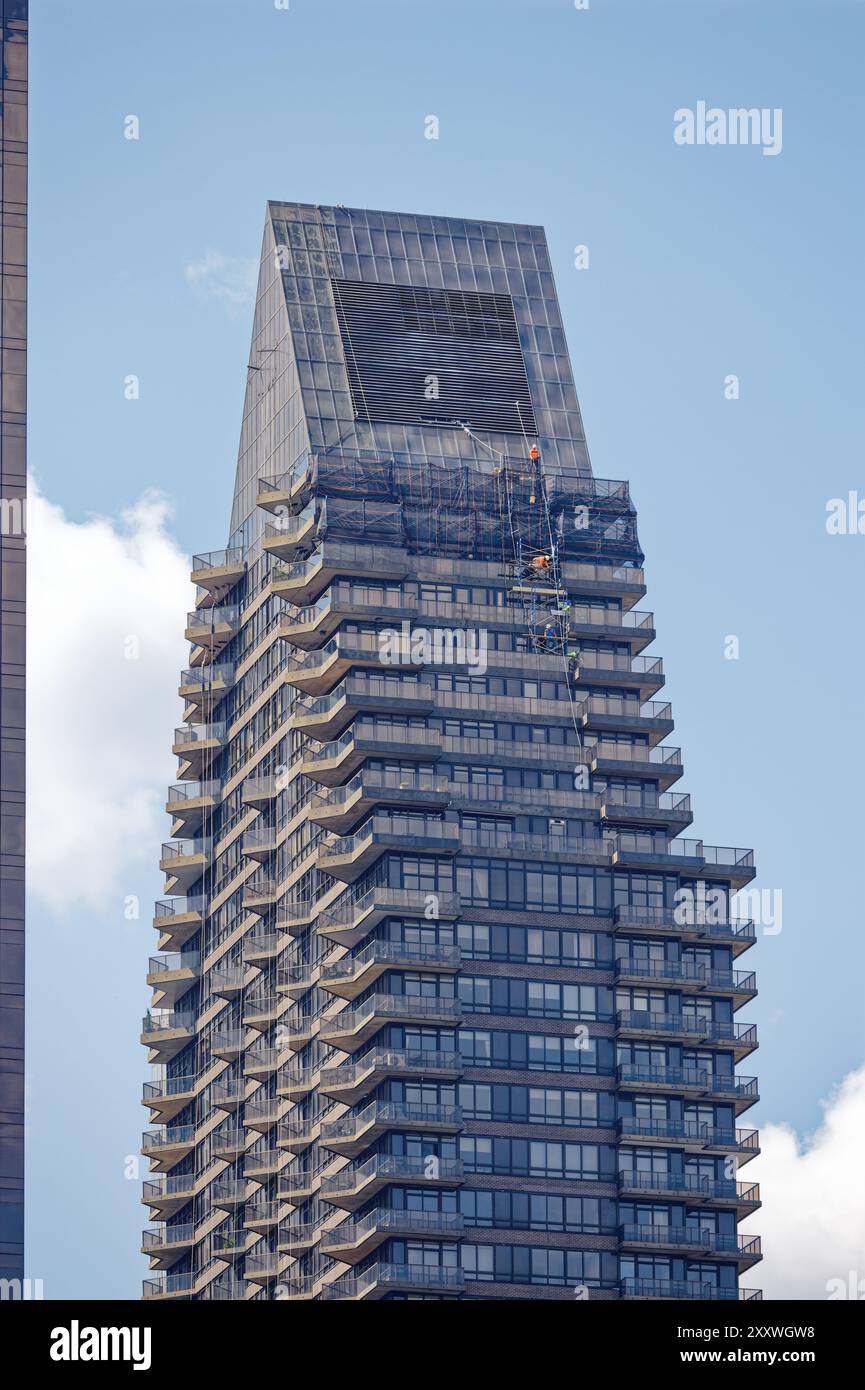 La manutenzione della facciata procede al 100 un Plaza, un alto edificio residenziale nero con tetto a cuneo e balconi nel Midtown East. Foto Stock