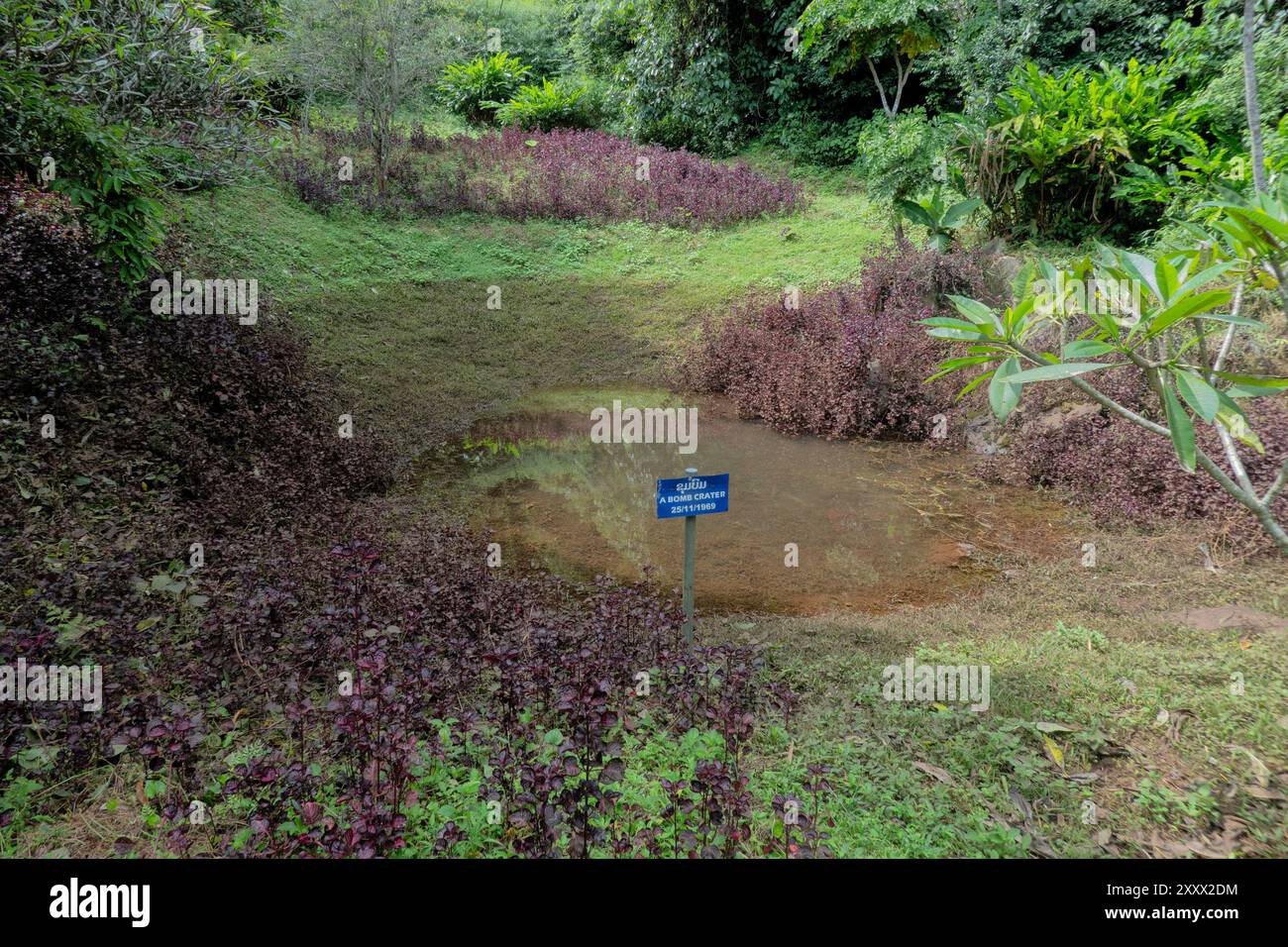 Bombardare il cratere con piante di Coleus rosse per ricordare lo spargimento di sangue nelle grotte di Vieng Xai, Viengxay, Houaphanh, Laos Foto Stock