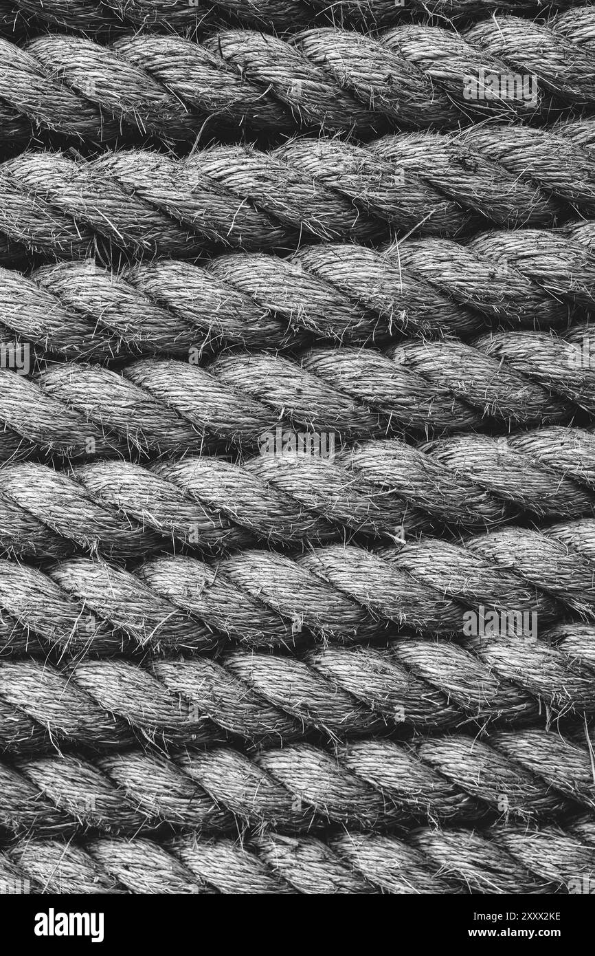Uno sfondo bianco e nero a cornice completa di spessa fune di spedizione strettamente avvolta insieme e realizzate in fibre naturali durevoli come la iuta in una vertica Foto Stock
