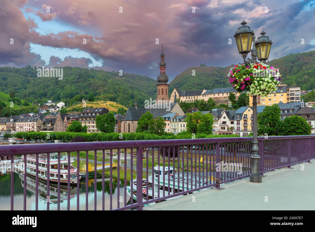 Vista del ponte di Cochem con lampione, chiesa ed edifici colorati sotto il cielo spettacolare, in Germania Foto Stock