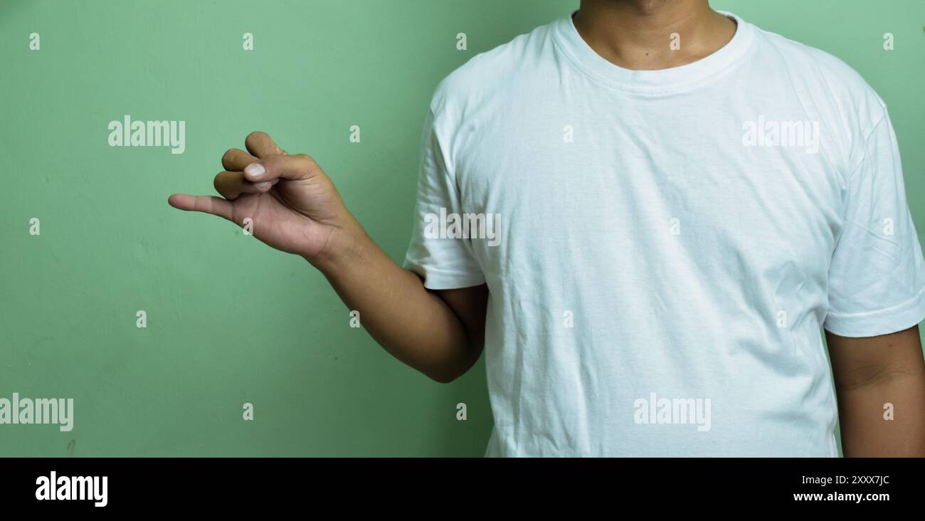 Giovane maschio che alza la mano mentre esprime pensieri senza parole, formando la lettera J con le dita Foto Stock