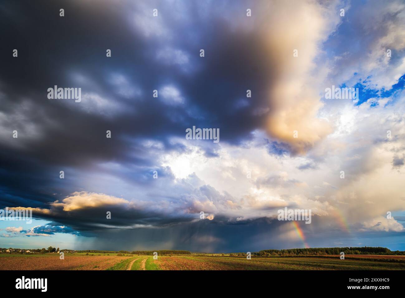 Tempesta nuvole nel cielo, pioggia all'orizzonte, stagione estiva. Due arcobaleni Foto Stock