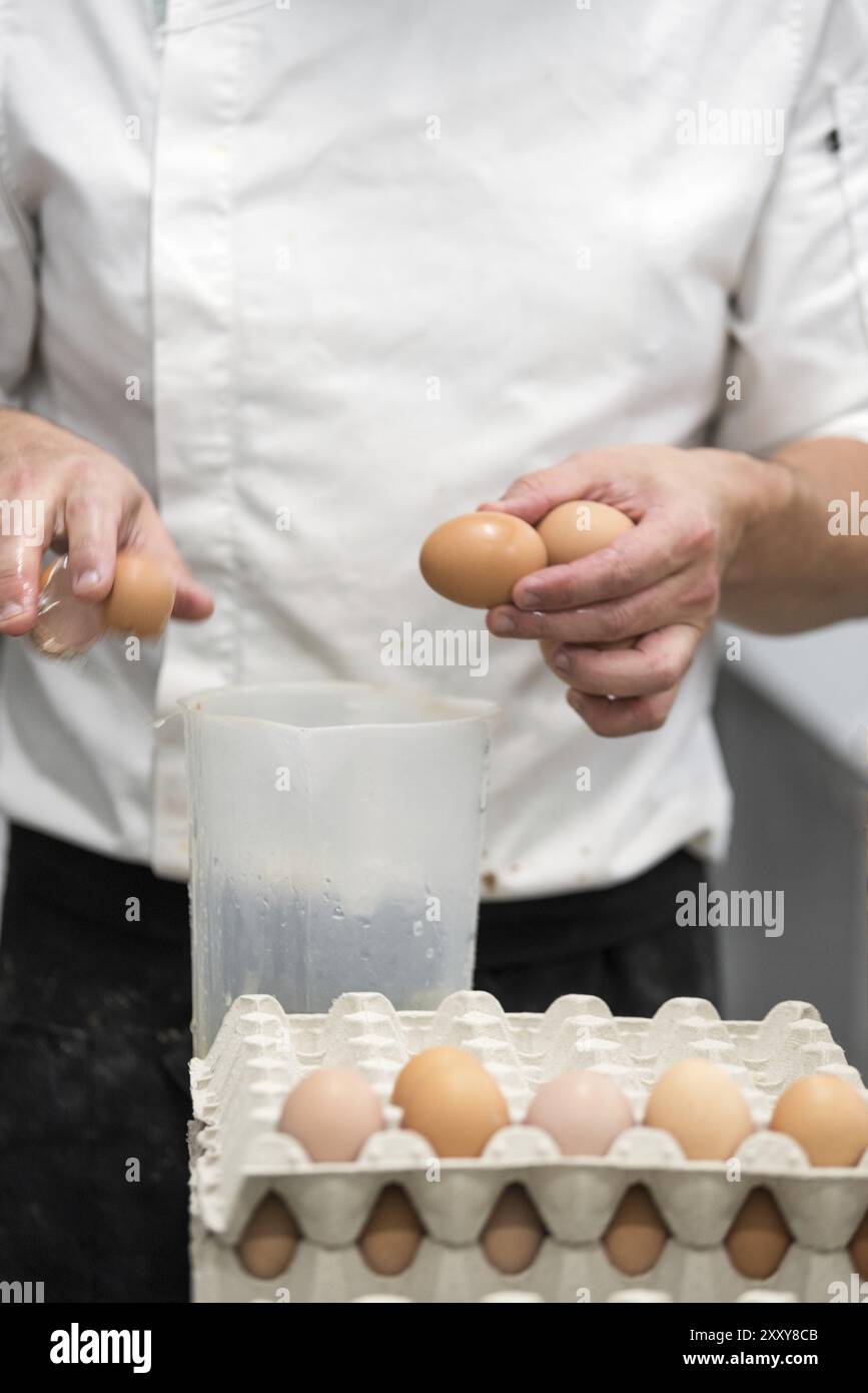 Pastry Chef rompere le uova per preparare la torta Foto Stock