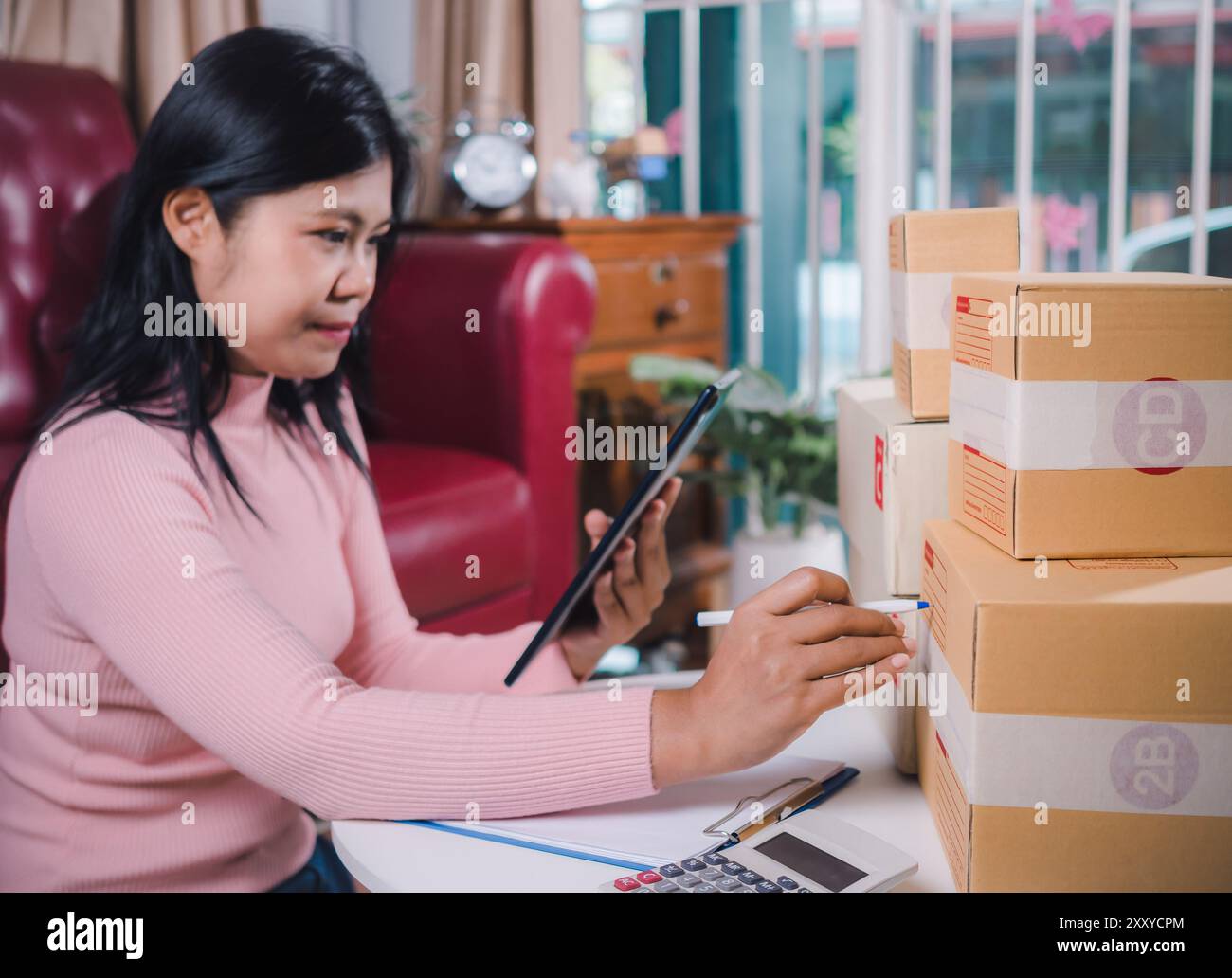 Donne d'affari che lavorano SME d'affari online a casa sua controllare l'elenco dei prodotti e l'ordine per il cliente e la consegna online per l'imballaggio pronto, controllo degli ordini Foto Stock