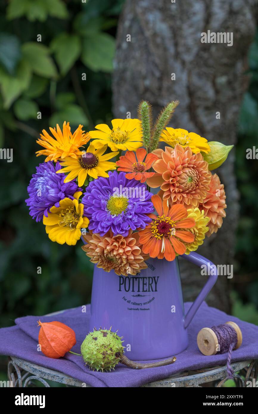 bouquet colorato con assaggi estivi, dahlia e zinnie in una brocca in giardino Foto Stock