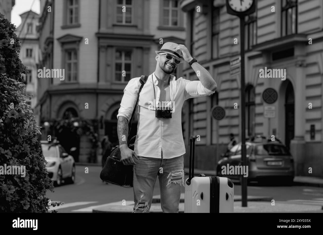 Viaggiatore, turista di moda. Viaggiatore turista in casual cappellino con valigia. Uomo turistico con borsa da viaggio in viaggio. Uomo con valigia a piedi Foto Stock