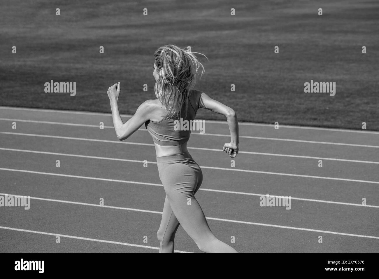 Jogger runner donna che corre all'aperto, runner. Fitness Woman allo stadio. Giovane atleta che corre sulla pista dello stadio. Donna in abbigliamento sportivo Foto Stock