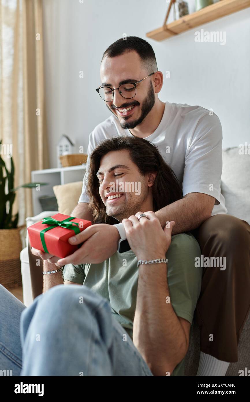 Un uomo sorprende il suo partner con un dono, entrambi irradiati di gioia. Foto Stock