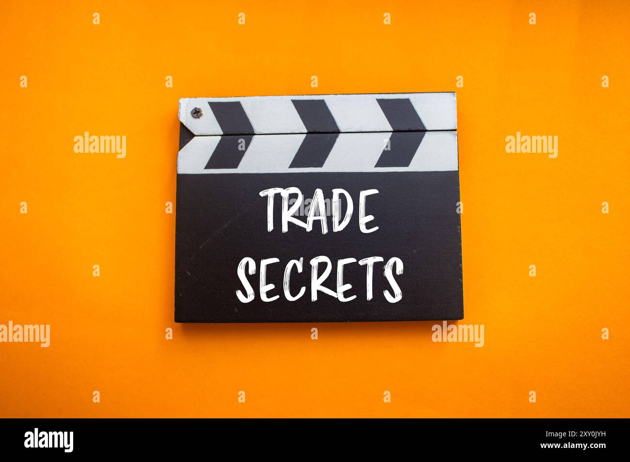 Messaggio sui segreti commerciali scritto sulla lavagna del film con sfondo arancione. Simbolo dei segreti commerciali concettuali. Copia spazio. Foto Stock