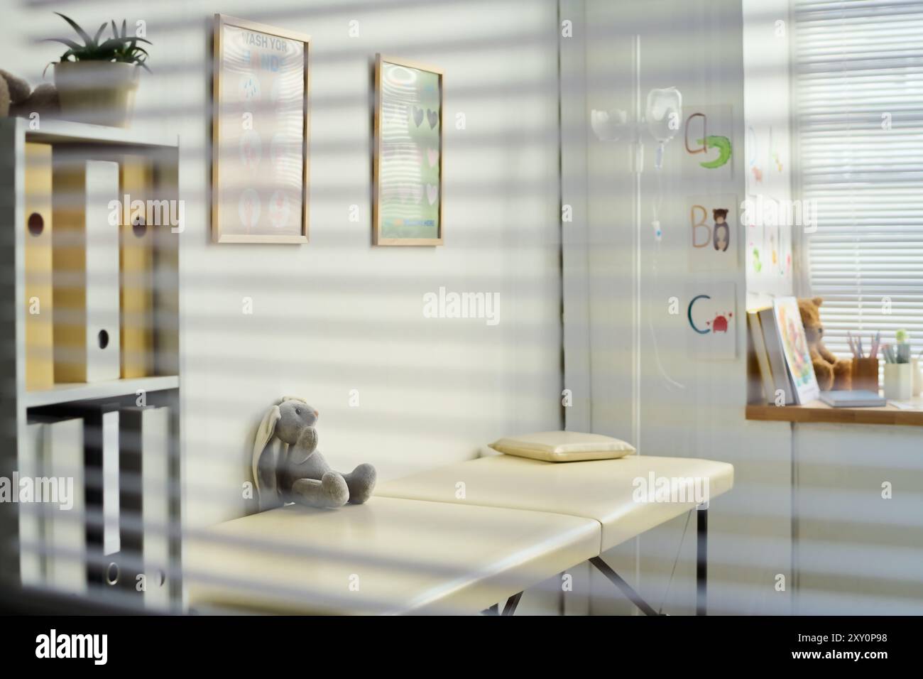 Area d'attesa della clinica illuminata con un peluche giocattolo sulla panca e poster educativi sulle pareti che la circondano, creando un'atmosfera invitante Foto Stock