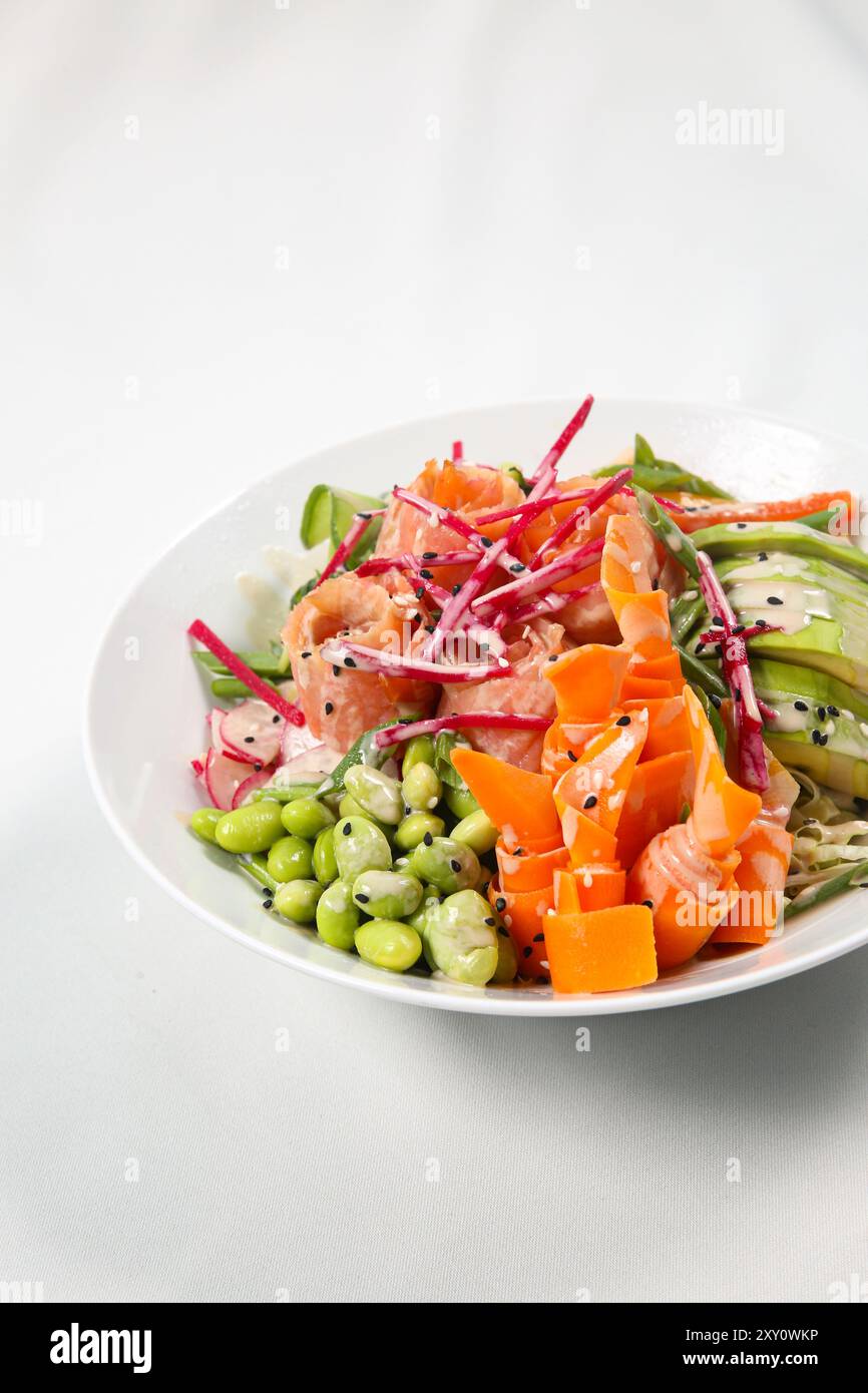 Ciotola hawaiana con salmone, avocado, ravanello, fagioli di edamame, cavolo rosso. Salsa di soia, lime e salsa di sesamo. tavolo bianco Foto Stock