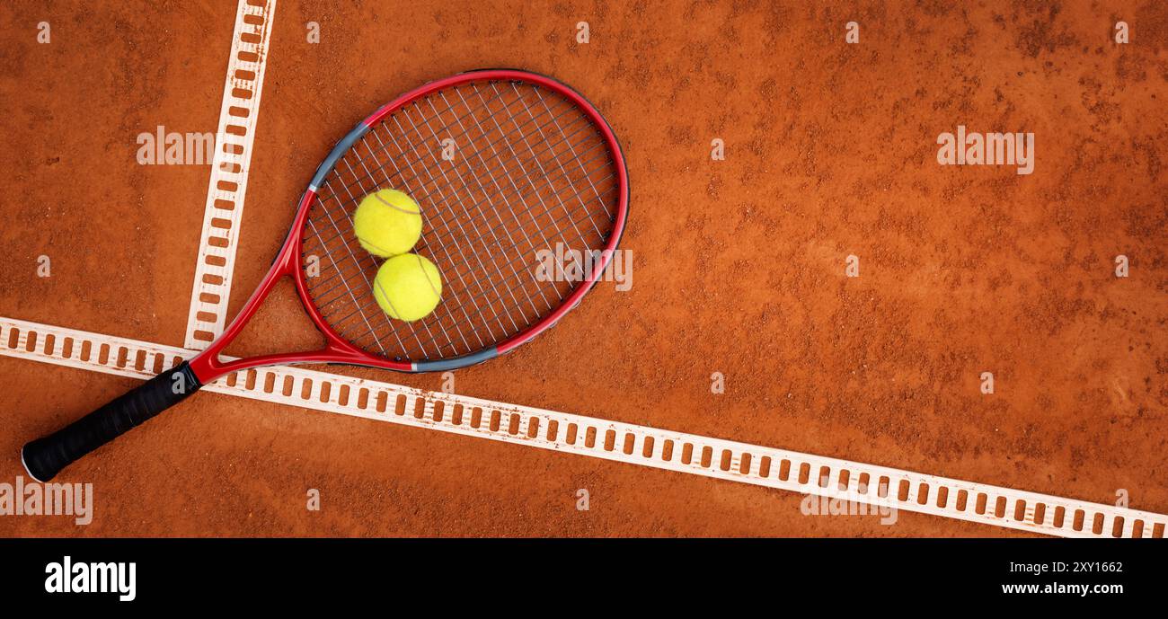 palle da tennis e racchetta sullo sfondo del campo in terra battuta. vista superiore con spazio di copia Foto Stock