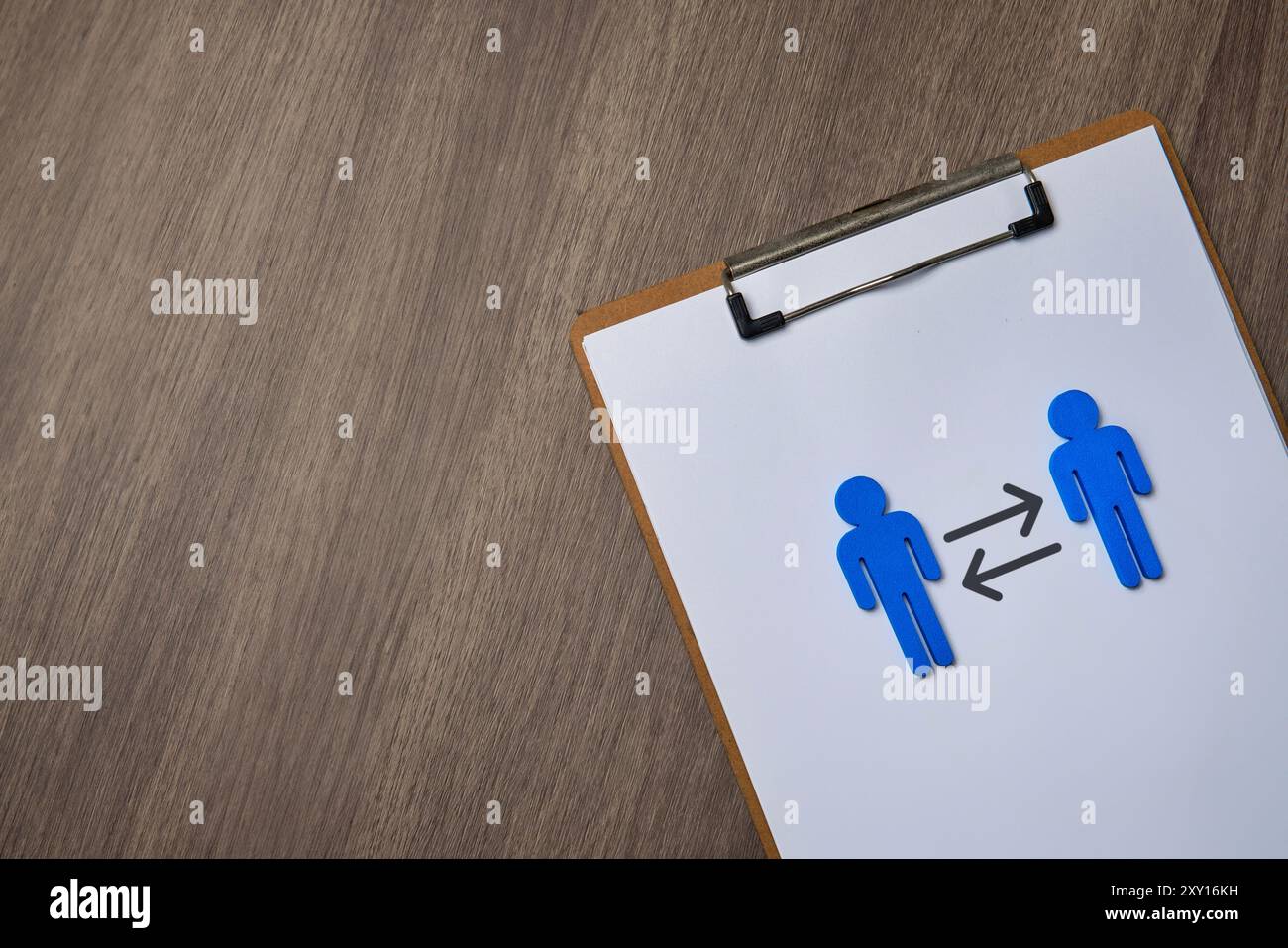 Due figure blu su una clipboard, rivolte l'una verso l'altra con frecce che puntano in entrambe le direzioni. Ciò simboleggia il concetto di rotazione del lavoro. Foto Stock