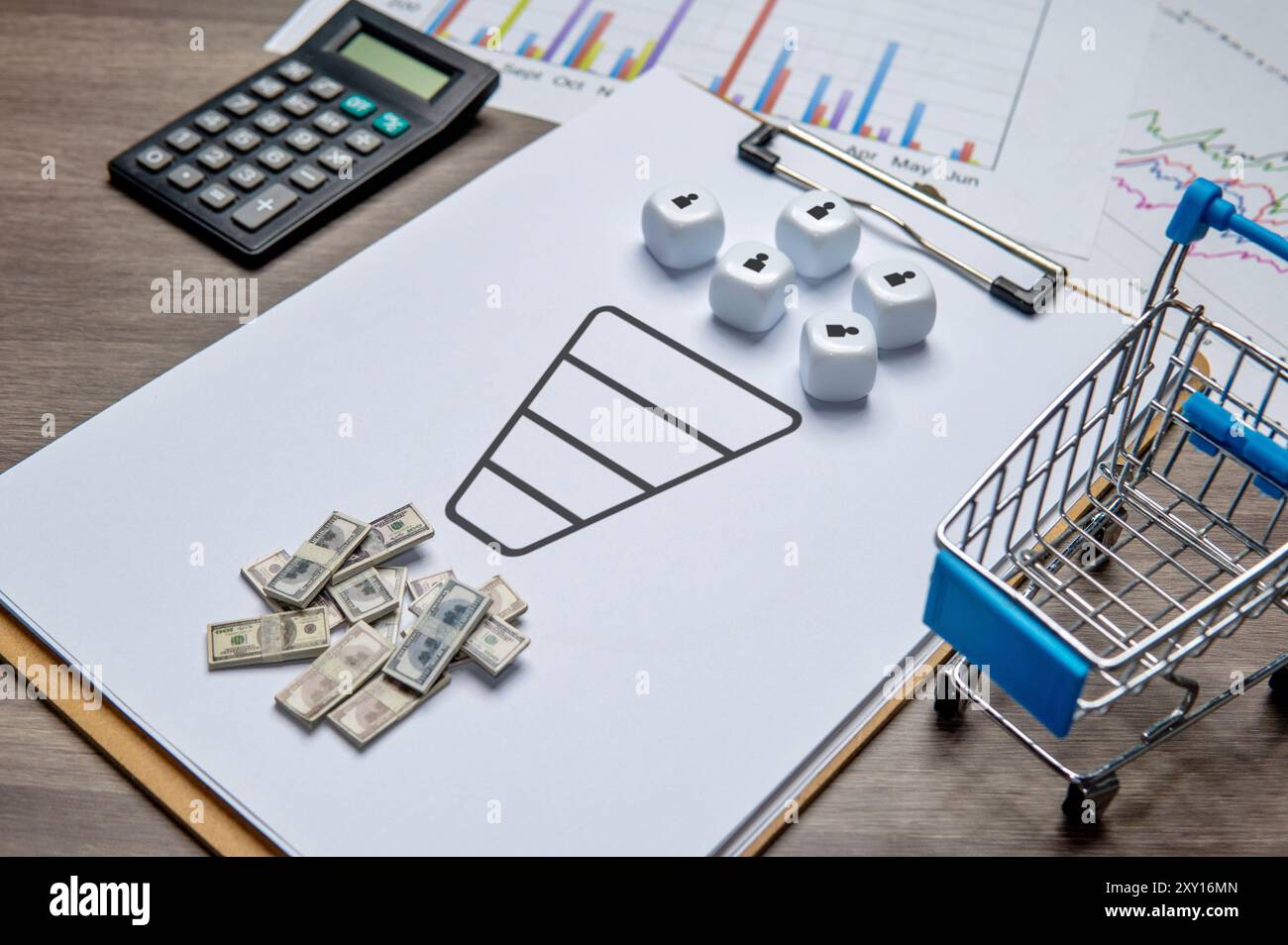 Una clipboard con un diagramma dell'imbuto di vendita e dadi che rappresentano i clienti. Nelle vicinanze ci sono soldi e un carrello, che simboleggia i ricavi e la conversione. Foto Stock