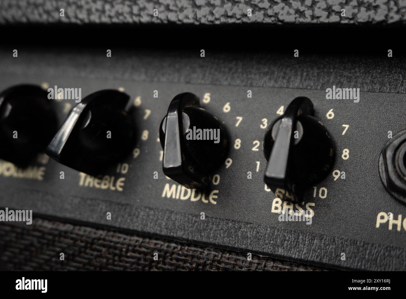 Primo piano delle manopole dell'amplificatore per chitarra nera con numeri su una superficie testurizzata. Foto Stock