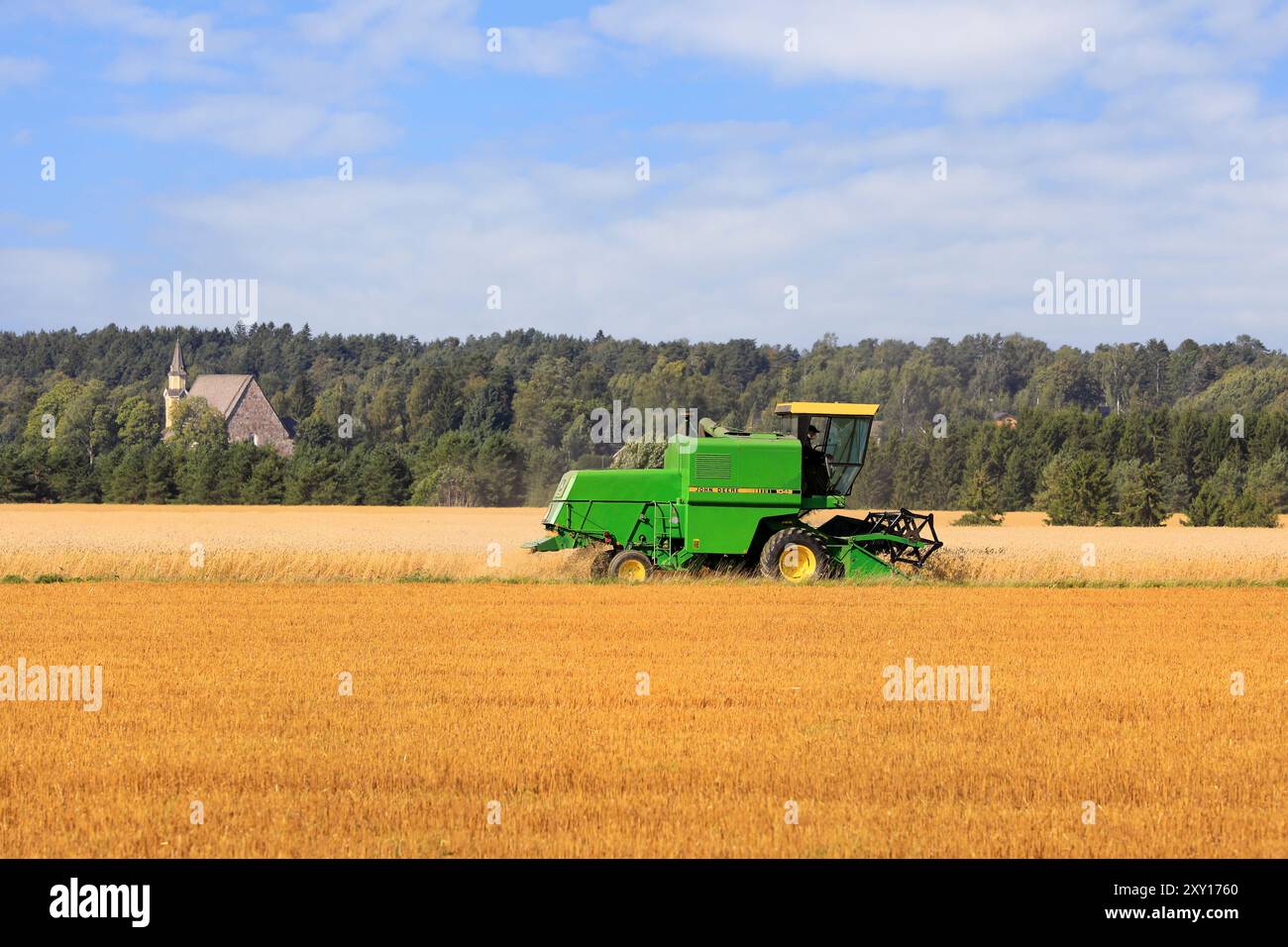 L'agricoltore raccoglie grano maturo con la mietitrebbia John Deere 1042 in una giornata di sole all'inizio dell'autunno. Copia spazio. Salo, Finlandia. 25 agosto 2024. Foto Stock