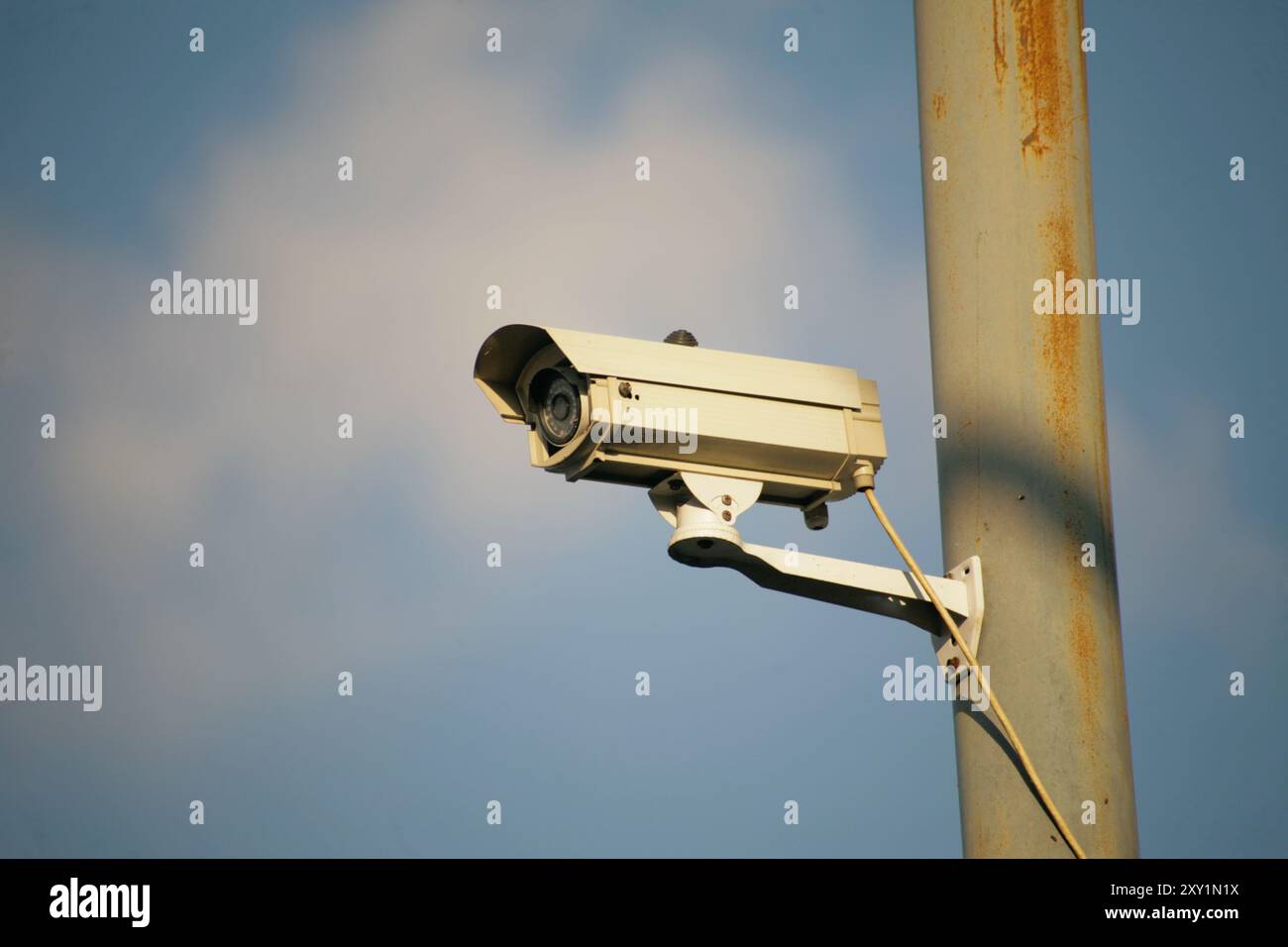 telecamera di sicurezza appesa al polo di alimentazione isolata su sfondo blu Foto Stock