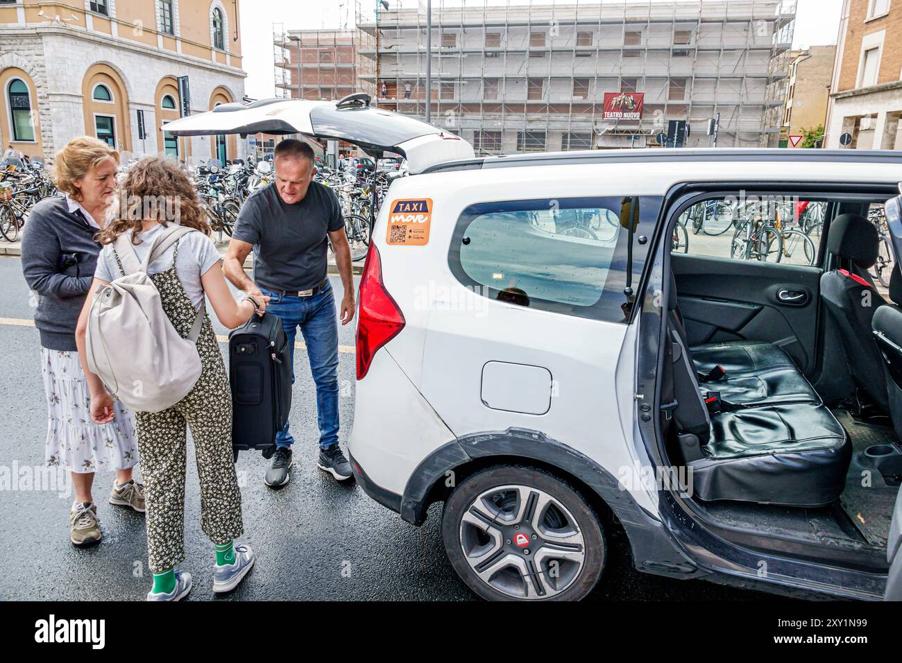 Pisa Italia, Piazza della stazione, stazione ferroviaria centrale di Pisa, taxi che raccoglie i passeggeri in arrivo, autista che carica bagagli SUV, donna Foto Stock