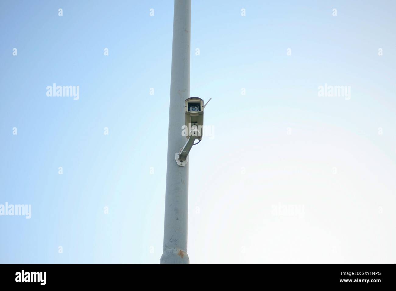 telecamera di sicurezza appesa al polo di alimentazione isolata su sfondo blu Foto Stock