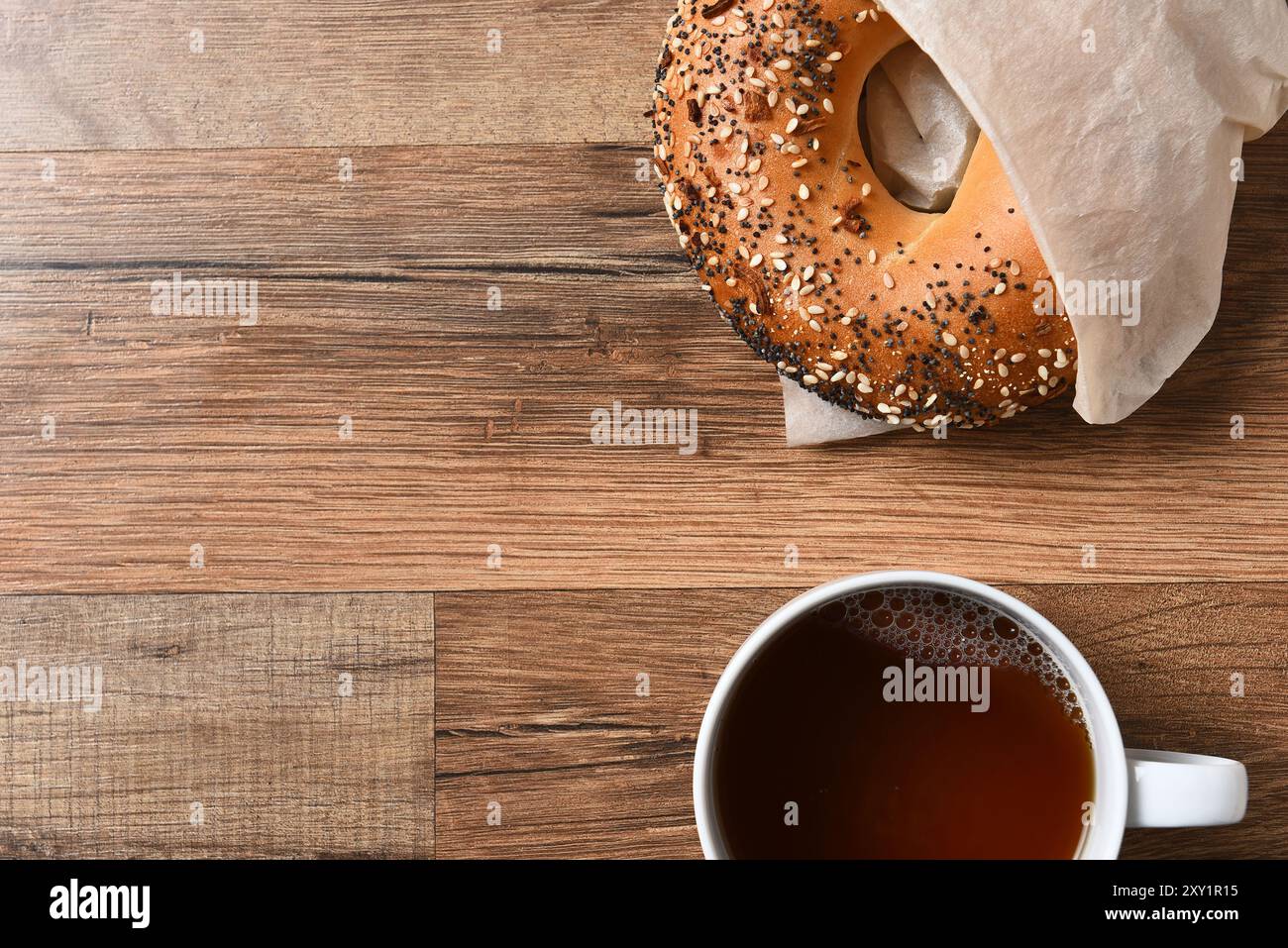 Bagel fresco e tazza di caffè caldo su un tavolo in legno rustico con spazio per fotocopie. Foto Stock