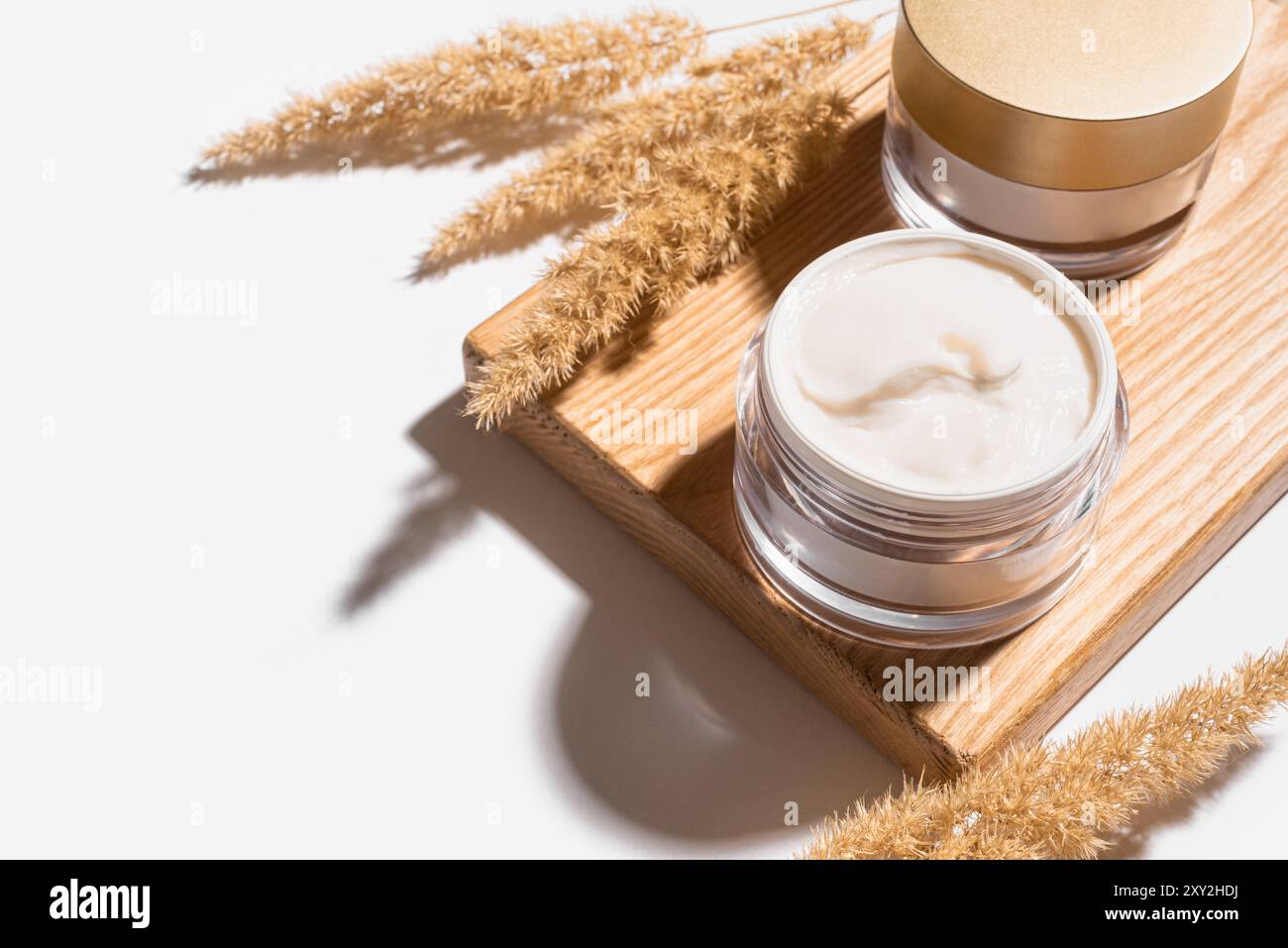 Prodotti cosmetici con crema di bellezza con canne secche o erba di pampas isolata su sfondo bianco. Trattamento viso anti-invecchiamento naturale della pelle, spazio di copia. Nourishi Foto Stock